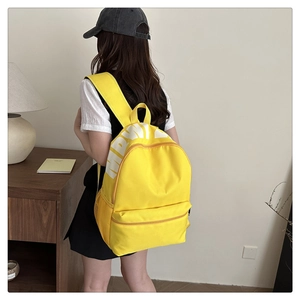 Detail of a bright yellow canvas backpack featuring white MRWI lettering and mesh side pocket
