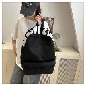 Detail view of large white letter logo print on black canvas backpack with side mesh pockets