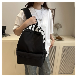 Detailed view of black nylon backpack with white lettering and side mesh pockets