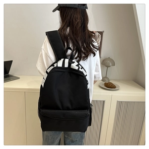 Detail of minimalist black nylon backpack with letter print and large front pocket