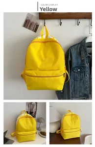 Macro detail of a yellow canvas backpack showing the large main zip and front pocket