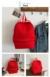Detail view of red school backpack showing front zip pocket and mesh side water bottle pockets