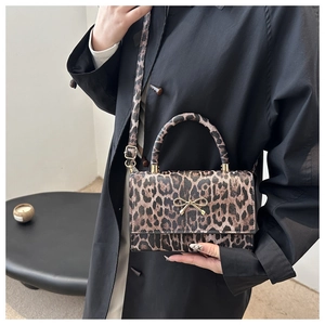 Detail of leopard print handbag featuring a gold metal bow and refined PU texture