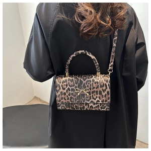 Detail of trendy leopard print shoulder bag featuring a gold bow clasp and matching strap