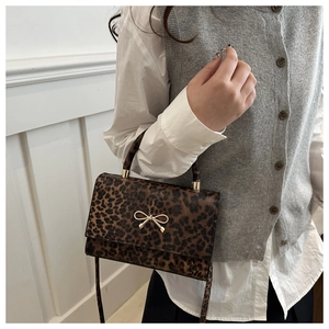 Detail of leopard print handbag featuring a gold bow metallic clasp and crossbody strap
