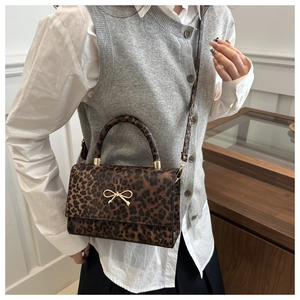 Close-up of leopard print handbag featuring a golden bow metal lock and handle detail