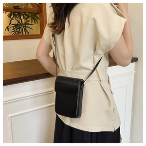 Minimalist black PU leather crossbody phone bag shown on model for size and style