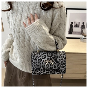 Close-up of leopard print crossbody bag with gold bow clasp and matching handle