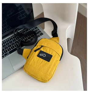 Gros plan sur un sac bandoulière en nylon jaune posé sur un PC pour montrer la taille