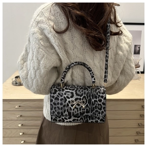 Detailed view of leopard print crossbody bag with golden bow on beige knit sweater