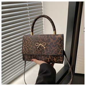 Detailed view of leopard print texture with golden bow buckle on a stylish handbag