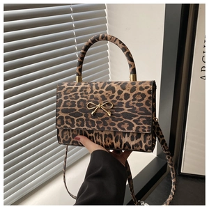 Detail of leopard print handbag featuring a gold bow buckle and textured handle