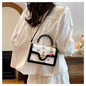 Vue détaillée du sac bandoulière blanc à motifs cerises et fermoir floral doré