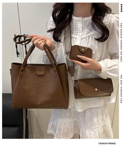 Detail view of dark brown croc-effect tote bag set with wide woven strap and accessories