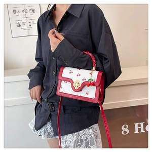 Détail du sac à main à motif cerise avec bandoulière rouge et fermoir doré