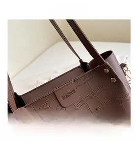 Detail of brown crocodile pattern handbag with gold studs and logo plaque on the side
