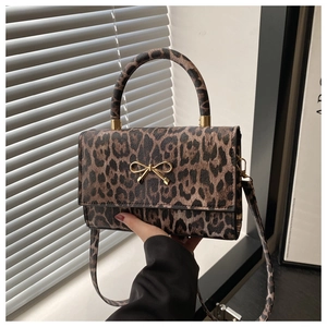 Close-up of leopard print bag with golden bow clasp and textured handle detail
