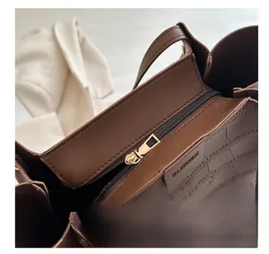 Detail of smooth gold zipper and dark brown crocodile embossed texture on tote bag
