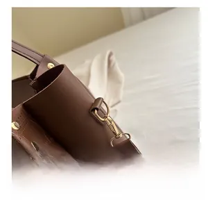 Close-up of brown crocodile embossed leather bag with ethnic woven strap and gold hardware