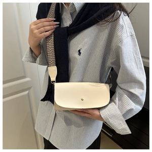 Detail of cream rectangular handbag with wide geometric strap and golden button closure