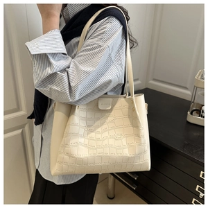 Dettaglio macro della borsa tote bianco crema con motivo a coccodrillo e logo