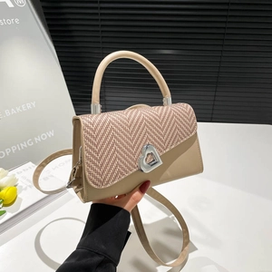Crossbody bag with woven texture, khaki leather, and silver heart clasp in a hand-held shot