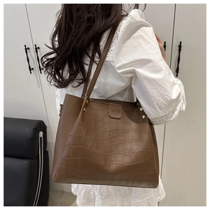 Dettaglio borsa shopper marrone scuro con trama a coccodrillo e rivetti metallici decorativi