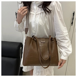 Brown crocodile texture tote bag detail featuring a geometric woven wide shoulder strap