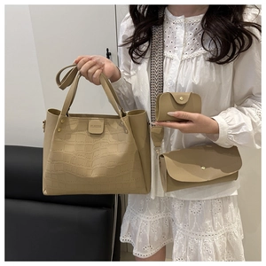 Detail view of beige crocodile embossed tote bag set with refined gold stud hardware