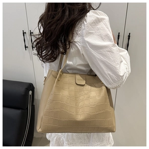 Dettaglio della borsa tote beige con motivo coccodrillo portata sulla spalla da dietro