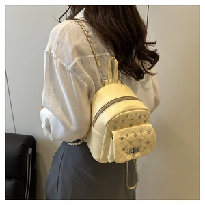 Mini-Rucksack in Creme mit Rautensteppung, Nieten und Kettenriemen am Modell getragen