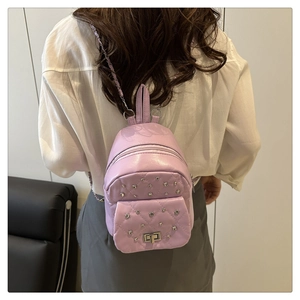 Detail eines lila gesteppten Minirucksacks mit Nieten an Model in weißer Bluse