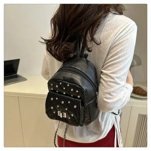 Detail eines gesteppten Mini-Rucksacks mit silbernen Nieten und Metallkettenriemen