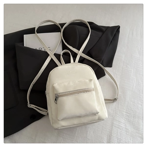 Dettaglio di uno zainetto mini bianco crema minimalista con spalline regolabili e tasca frontale