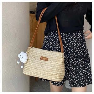 Detail of woven straw bucket bag with leather strap and a cute cloud charm accessory