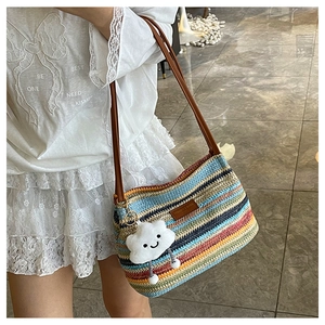 Detail of colorful rainbow striped woven bucket bag with leather strap and cloud charm