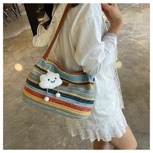 Detail of colorful striped woven bucket bag with cute white cloud plush pendant