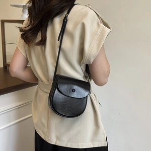 Retro black faux leather saddle bag with adjustable shoulder strap shown on model