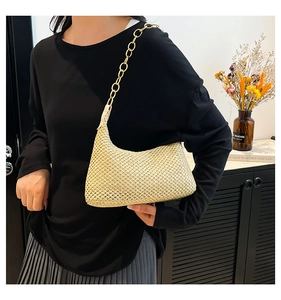 Dettaglio borsa hobo in paglia intrecciata con catena in acrilico sulla spalla