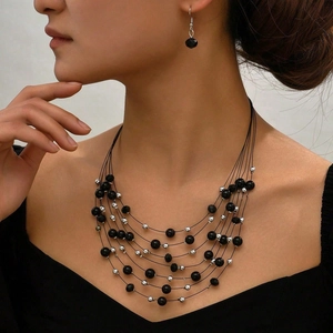 Détail d'un collier multicouche en perles noires et boucles d'oreilles sur un mannequin