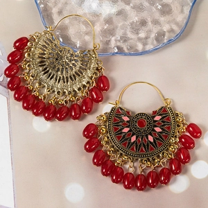 Detailed macro view of vintage fan-shaped golden earrings with red droplet beads
