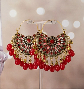 Detail of bohemian fan-shaped drop earrings with retro gold metal and deep red beads