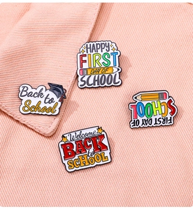 Gros plan de quatre pin's en émail thème rentrée scolaire avec crayons et toques