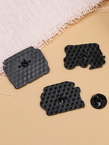 Détail du revers d'une broche alphabet avec finition noire texturée et fermoir papillon