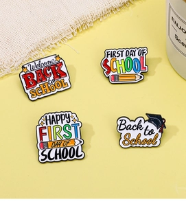 Détail de quatre épingles en émail colorées pour la rentrée scolaire sur fond texturé