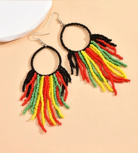 Detail of bohemian beaded hoop earrings with colorful fringe in red yellow green and black