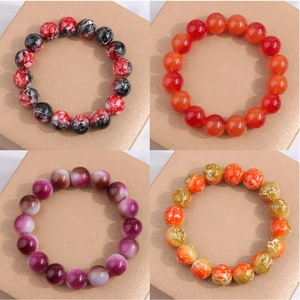 Détails de quatre bracelets en perles rondes de couleurs avec motifs variés sur un coffret