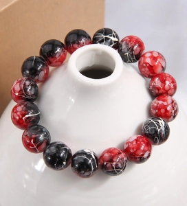 Détail du bracelet en perles de marbre rouge et noir avec taches blanches sur col céramique