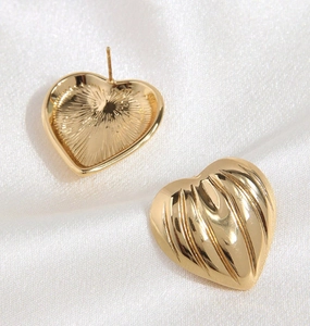 Detailed front and back view of gold heart stud earrings on elegant white silk fabric