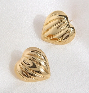Macro detail of golden heart earrings featuring a unique 3D ribbed wavy metal texture